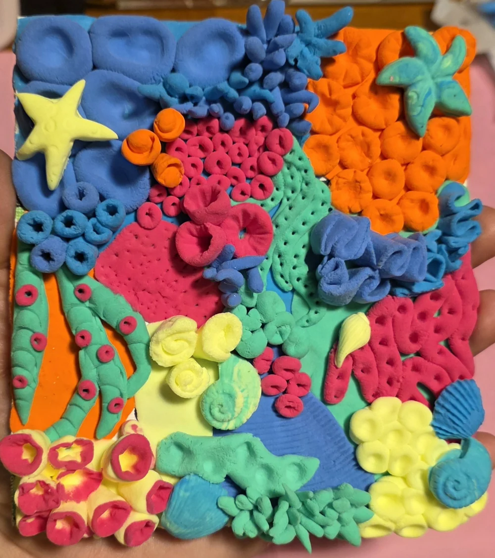A colourful raised composition with fish, stars and coral-like shapes.