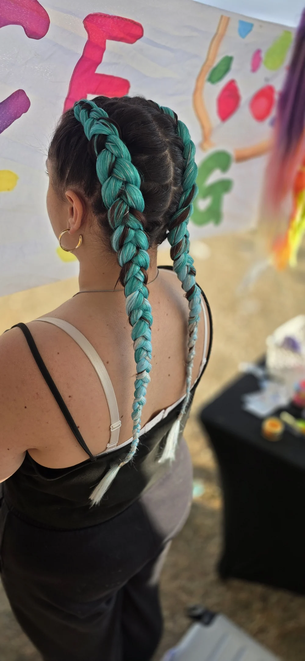 Long turquoise braids viewed from behind.