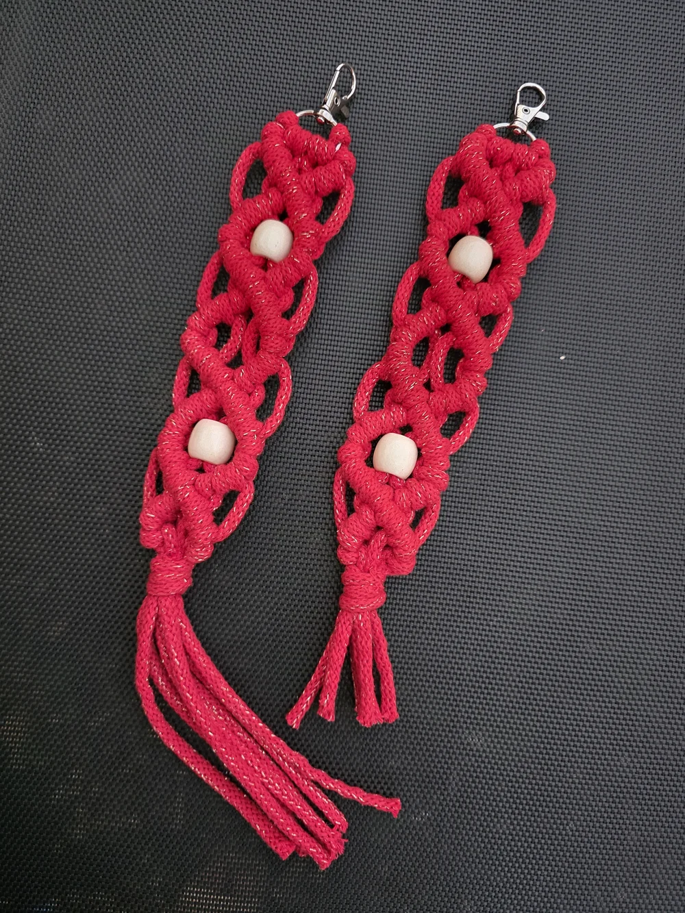A pair of pink knotted macramé earrings with pale beads.