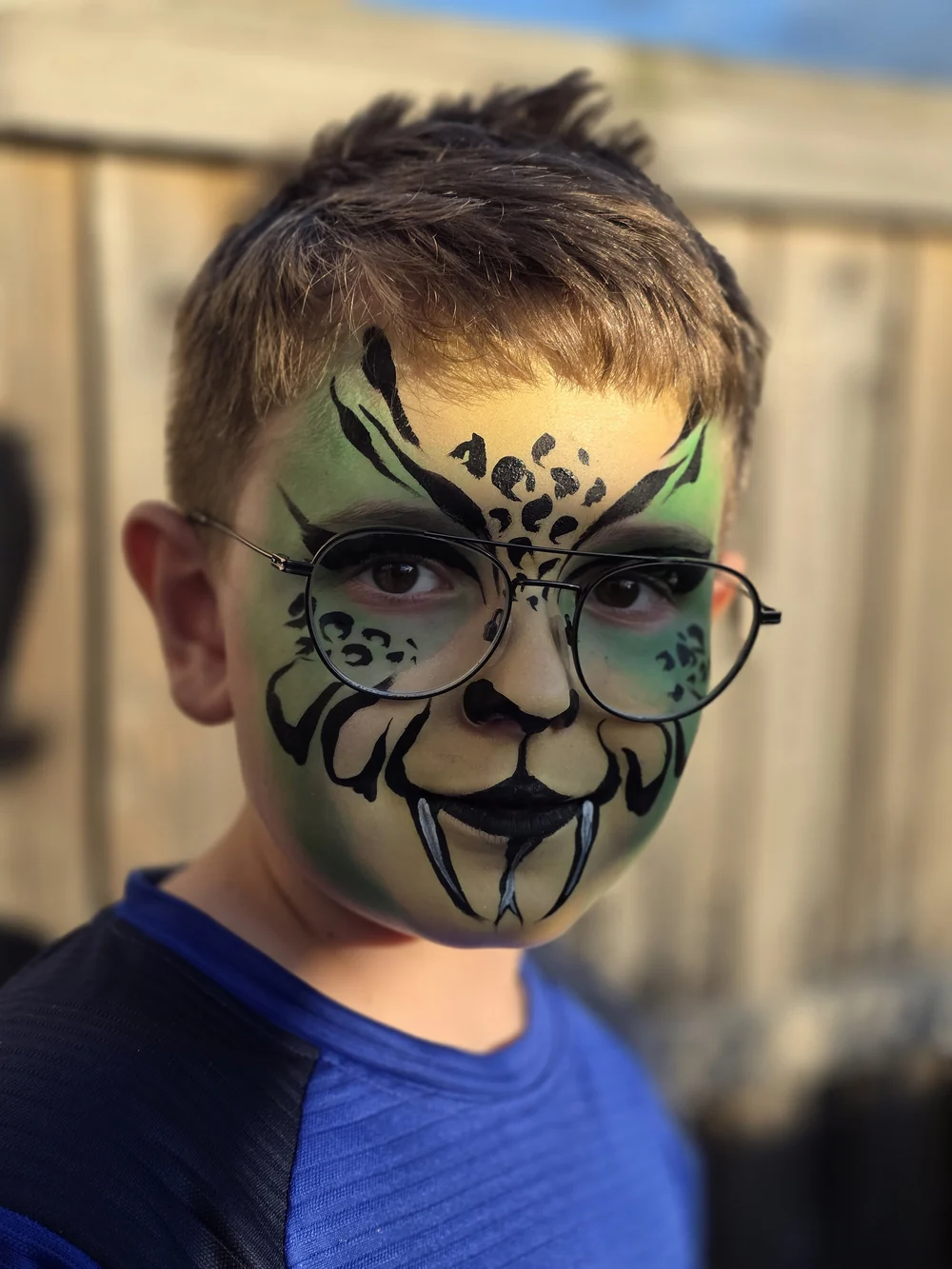 Green and black tiger face painting with detailed stripes.