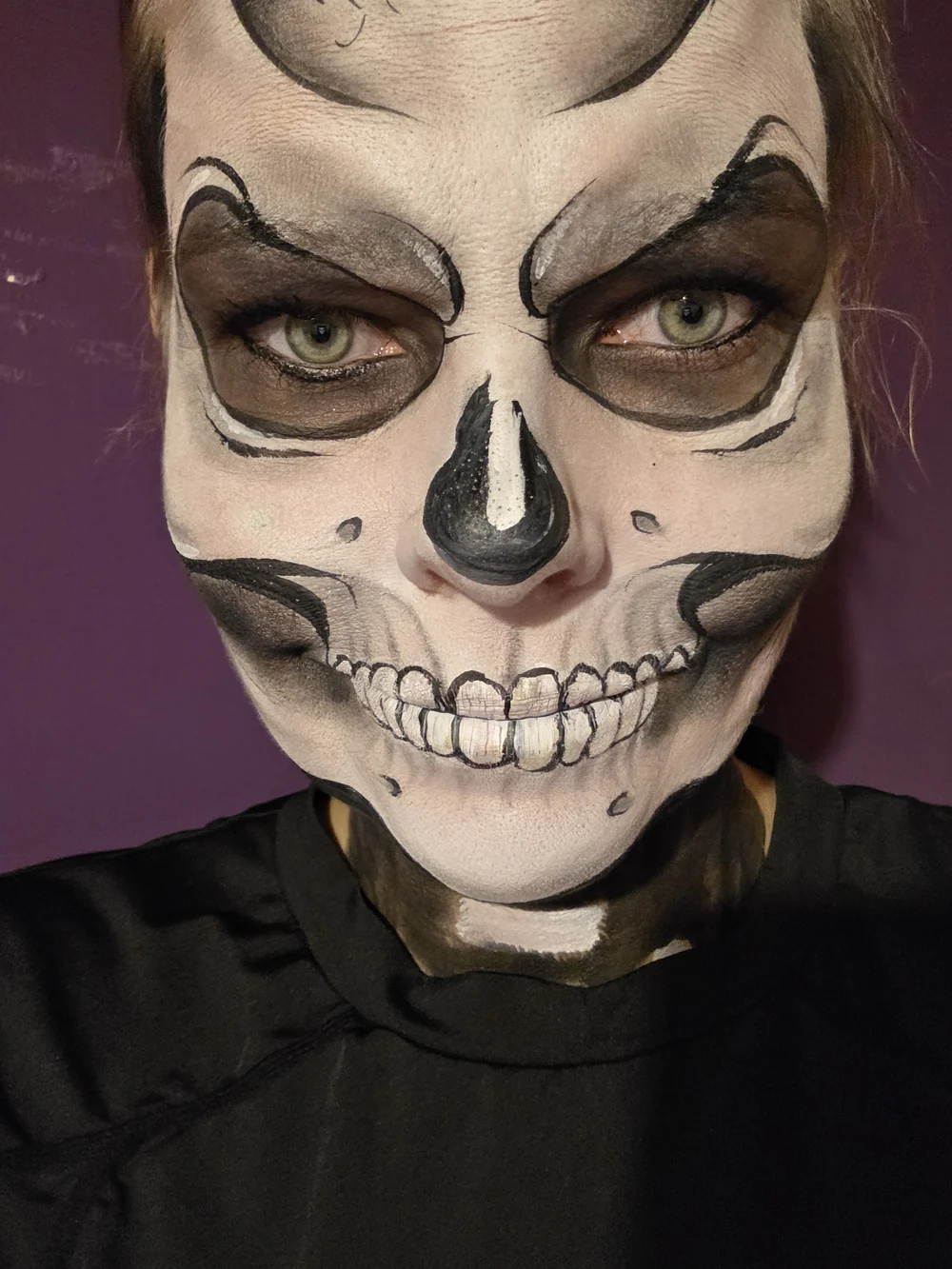 White skull face painting with dark eye sockets and fine teeth.