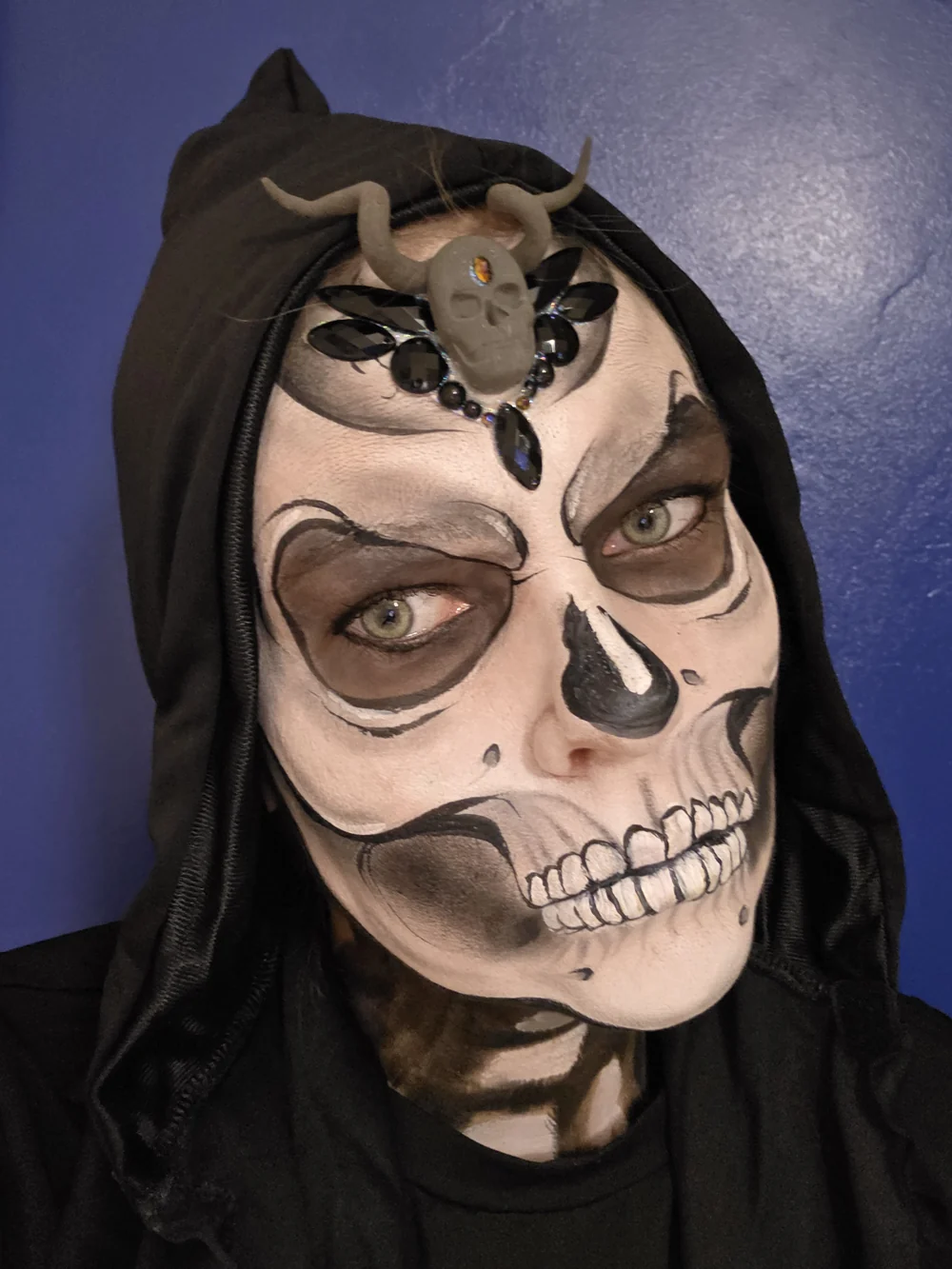 White skeleton face painting beneath a black hood.