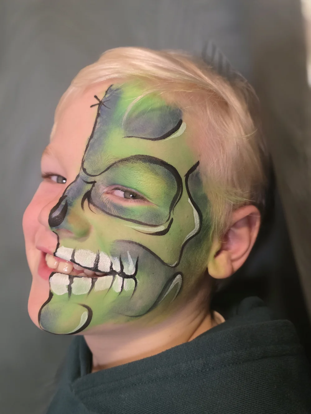 Green half-skull face painting with black shading.