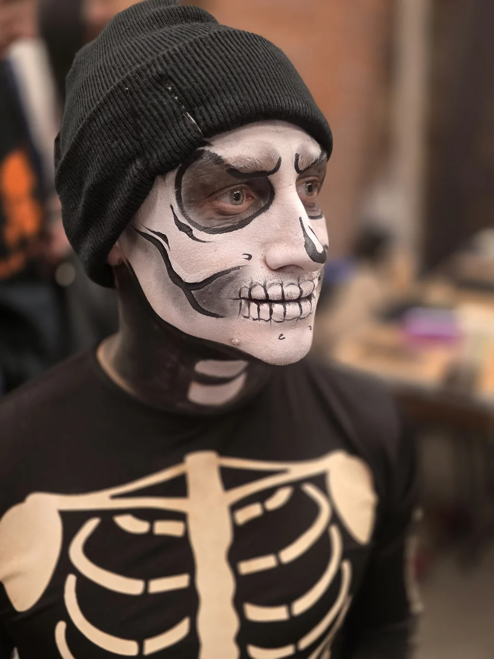 Skull face painting with a black beanie and skeleton costume.
