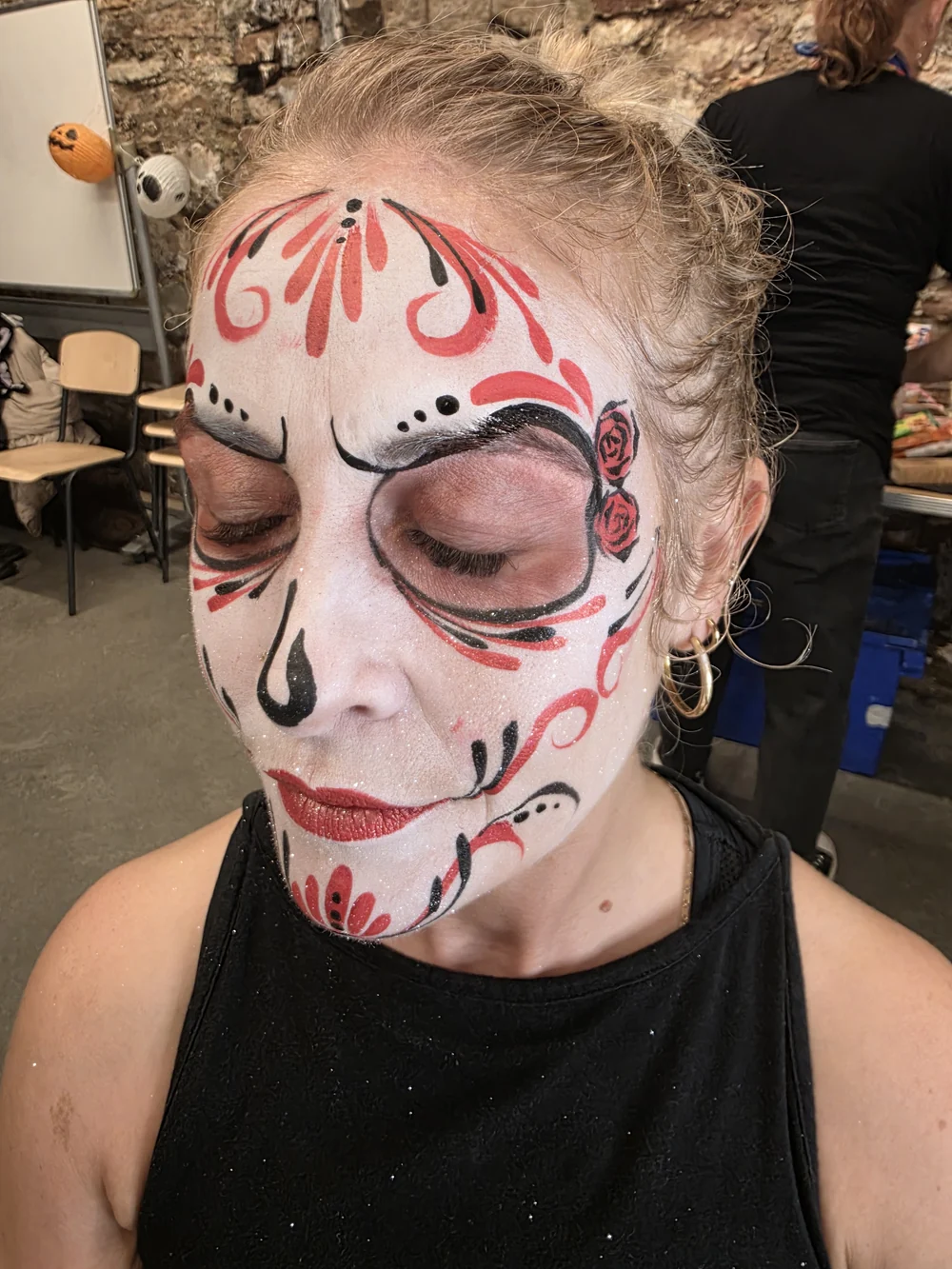White skull face painting with delicate red flourishes.