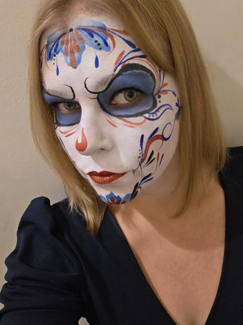 White skull face painting with blue and gold flourishes.