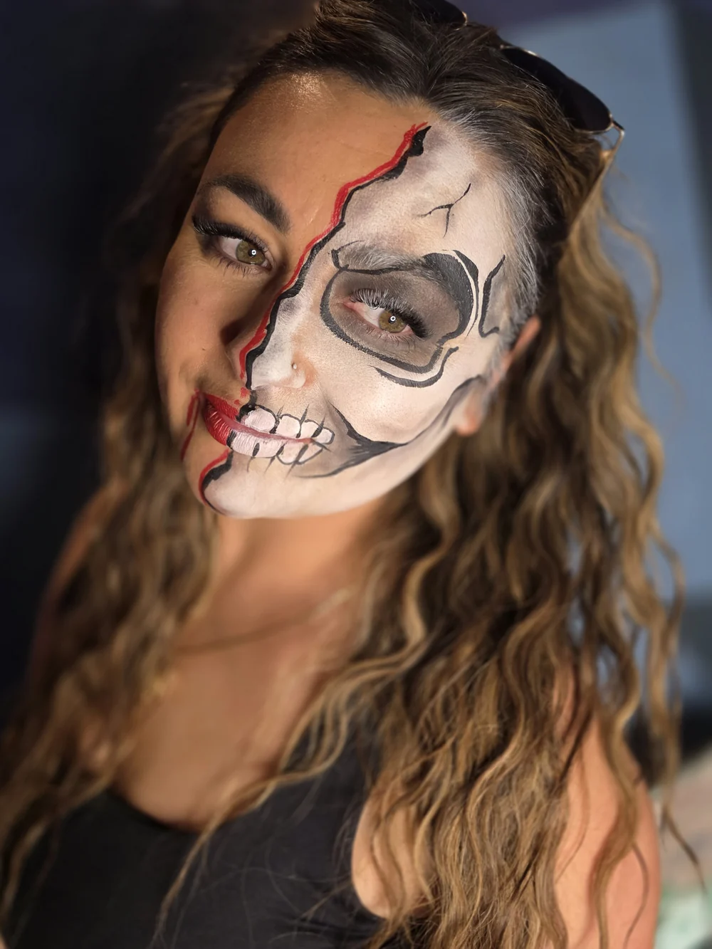 Half-skeleton face painting with red and gold details.