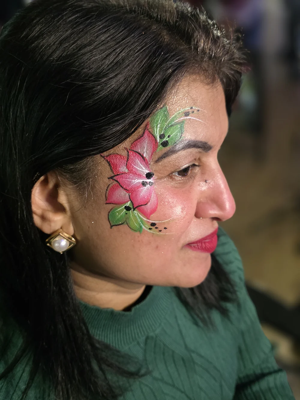 Pink flowers and green leaves painted across a cheek.