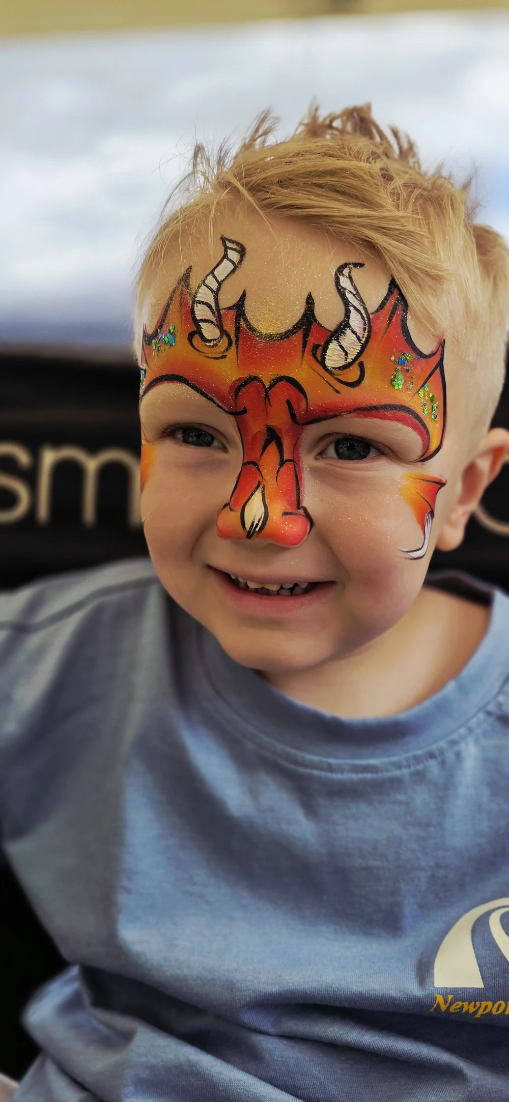 Orange and yellow dragon-style face painting with dark outlines.