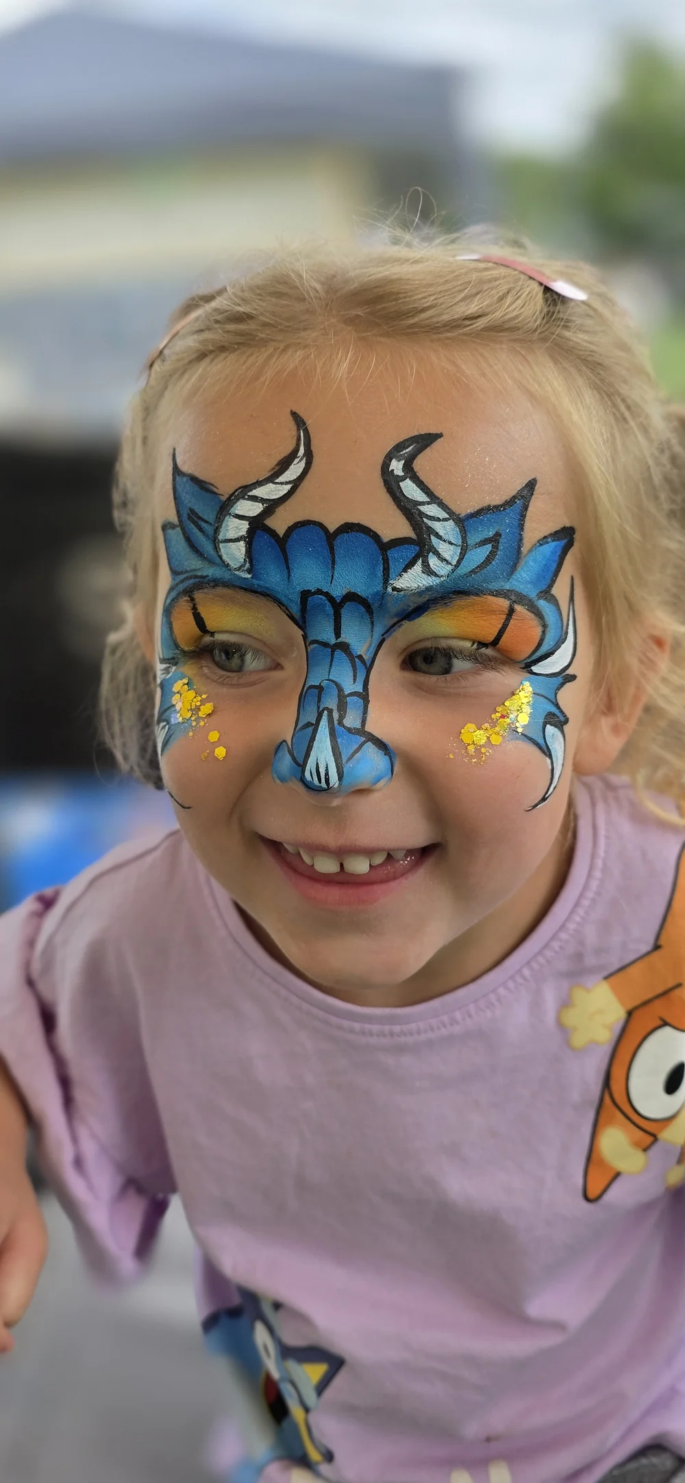 Blue butterfly-style face painting with yellow and white highlights.