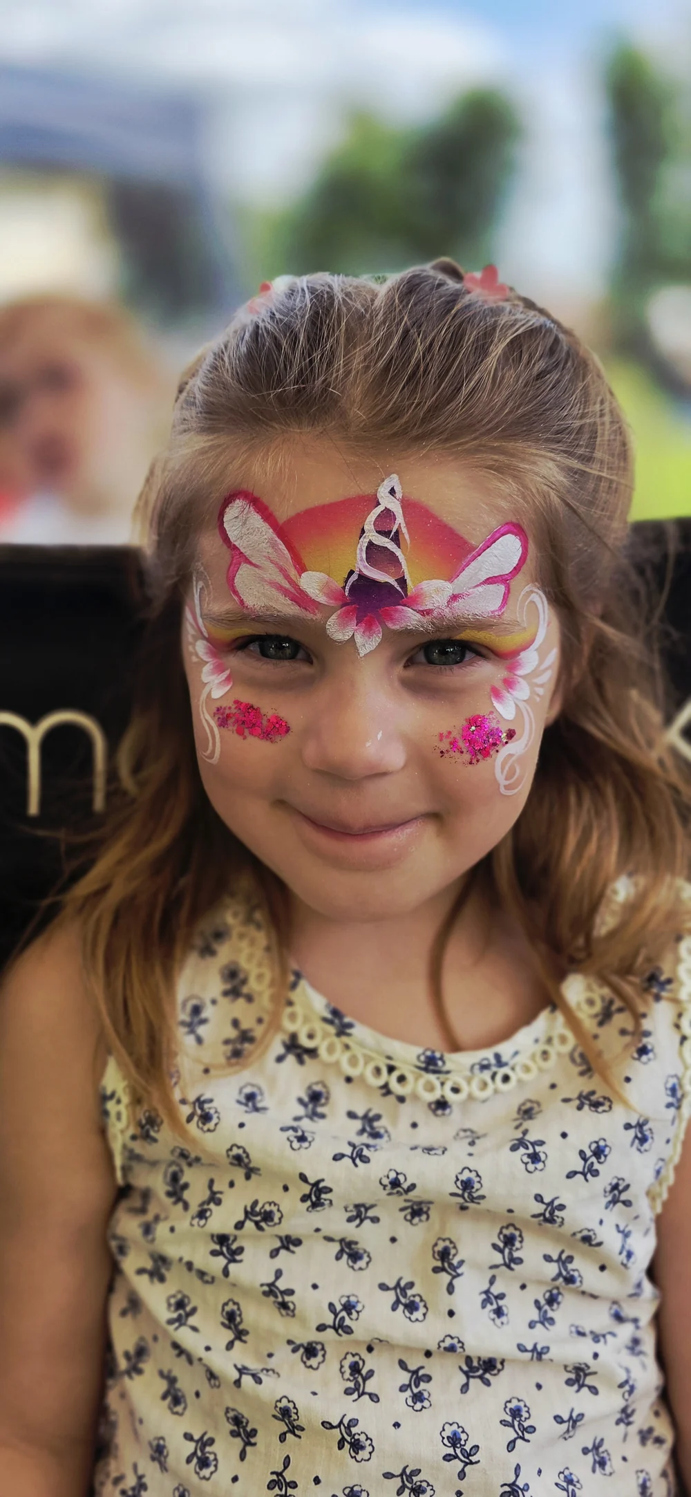 Pink and yellow butterfly-style face painting with white details.