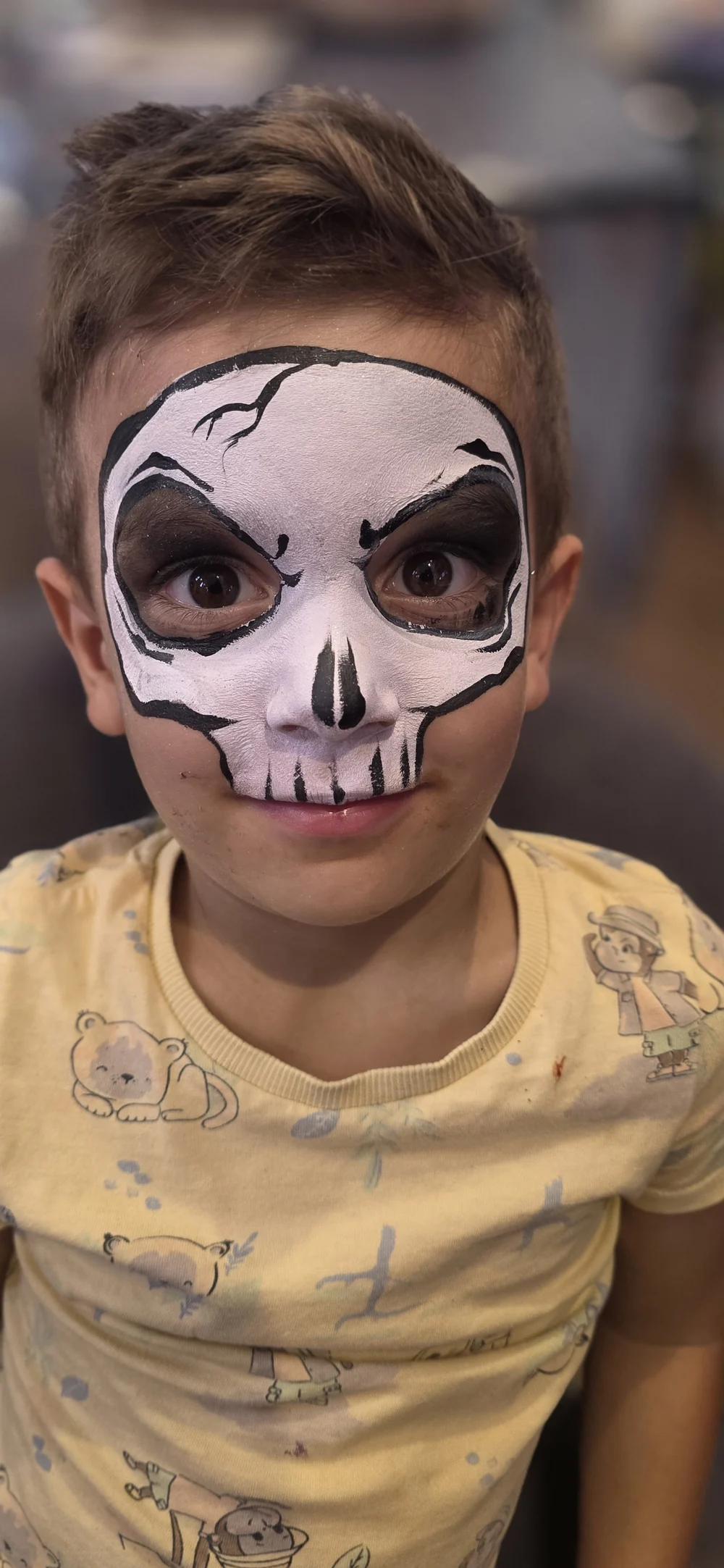 White skull face painting with dark eyes and delicate black lines.