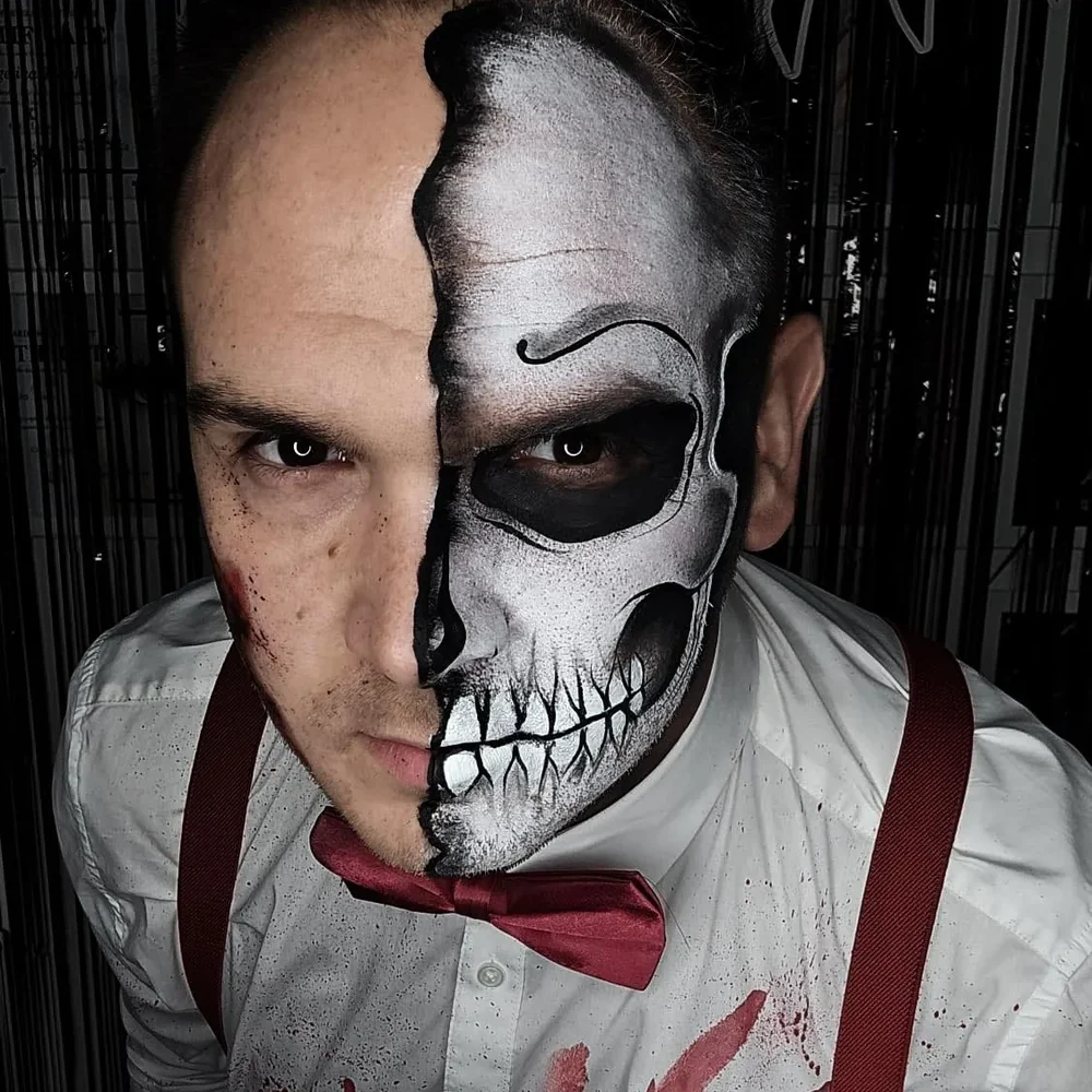 A portrait showing detailed half-skull face painting and a red bow tie.