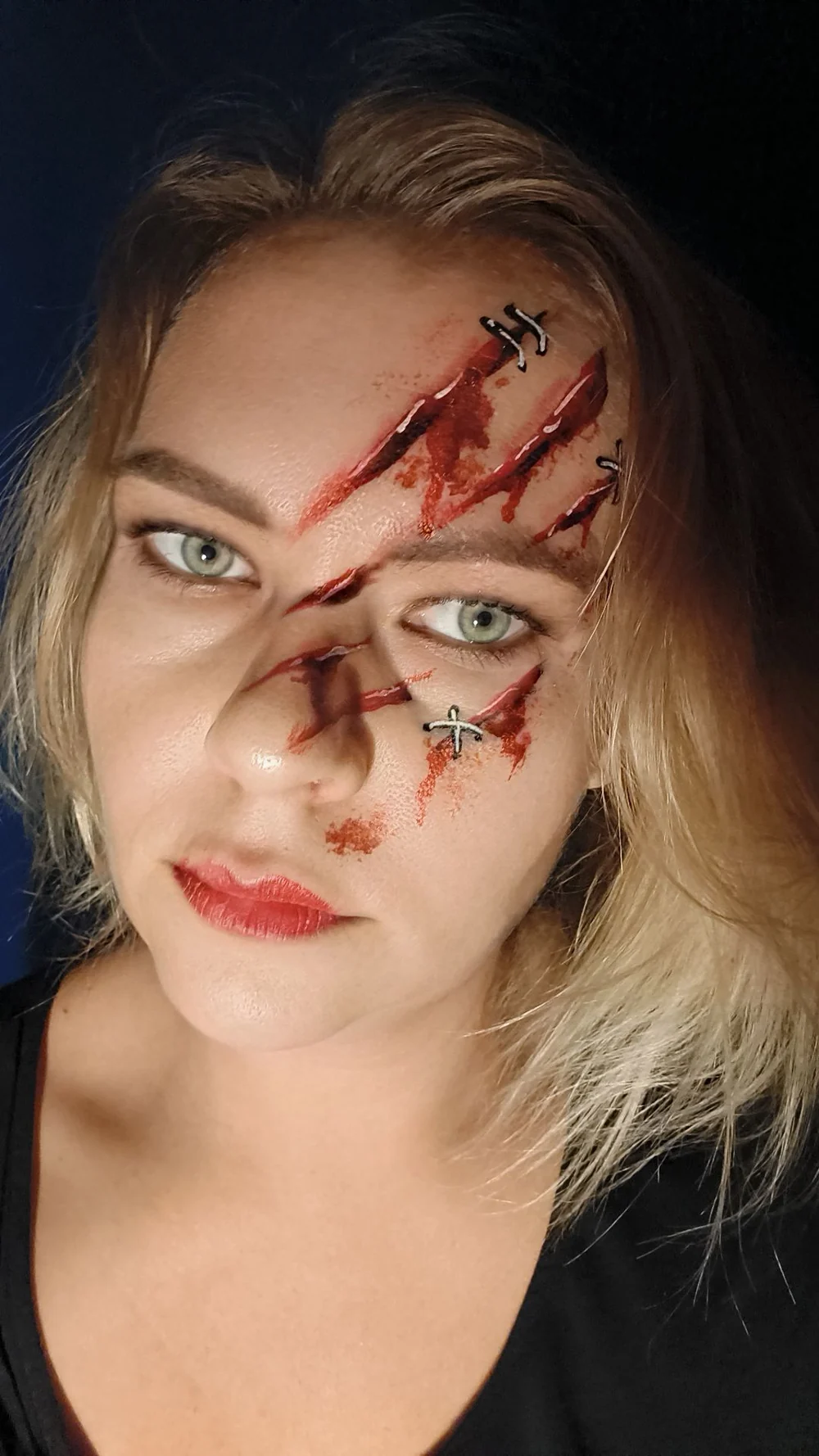 Half-face Halloween painting with red wound-style details.
