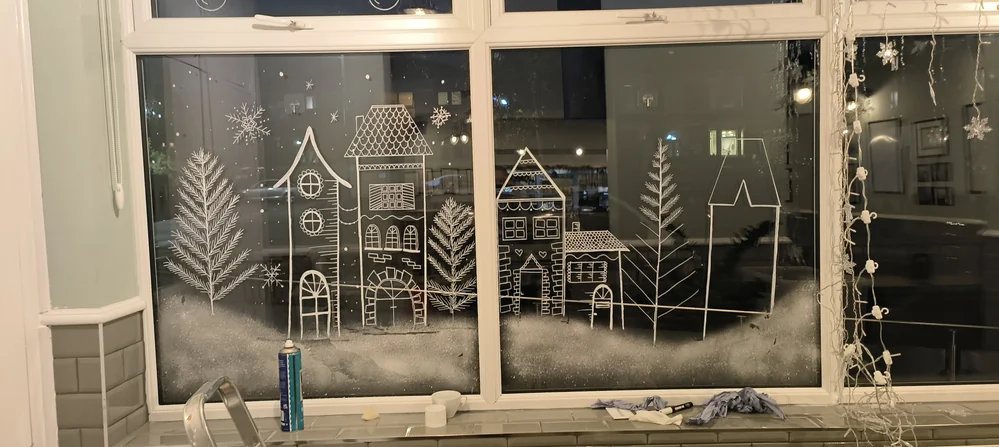 White painted winter houses and trees across a wide window.